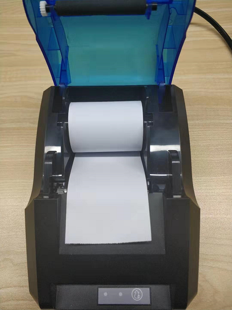 打印机接好电源线和数据线,开机并插入电脑;如下图所示,放好小票纸,再